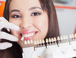 woman comparing teeth to veneer chart