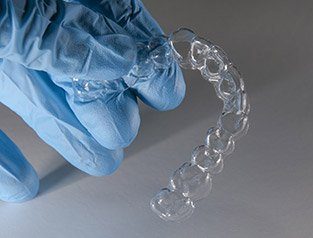 hand with glove holding invisalign