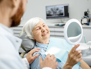 An older woman smiling and looking at a mirror
