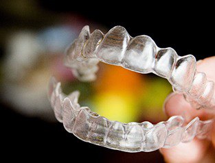 close up of person holding Invisalign clear aligners