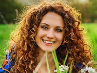 woman with curly hair smiling outside