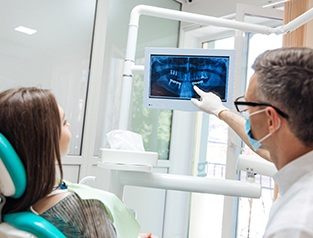 Implant dentist in Greenfield pointing at X-ray with patient