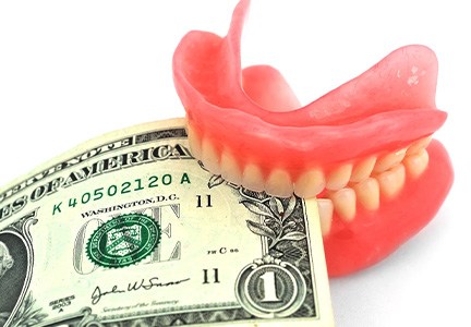 Copy of a set of dentures biting down on a dollar bill