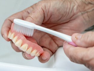 Patient cleaning their removable denture