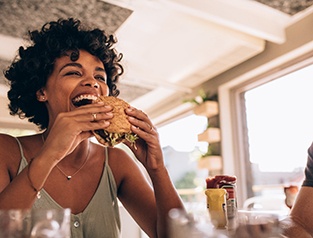 Happy Greenfield patient eating comfortably with dental bridge