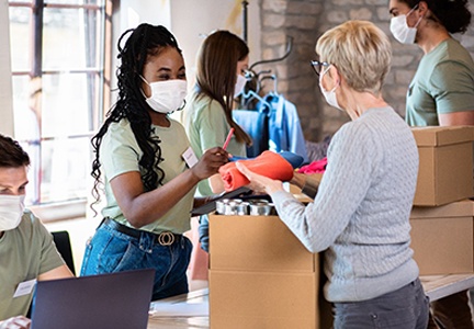 community food drive where woman is donating a box of canned food and clothes