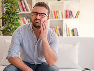Man with toothache sitting on couch