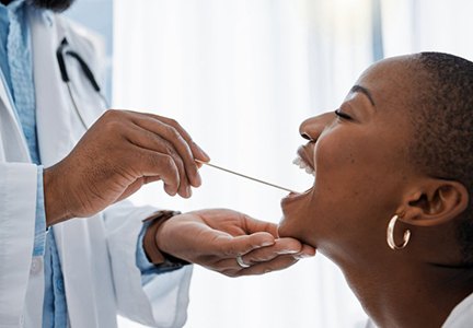Paciente abre su boca mientras el dentista le examina los dientes.