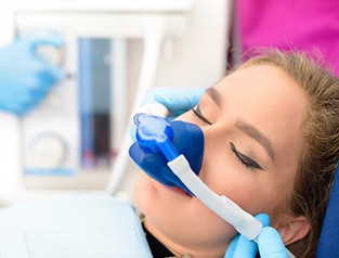 Mujer relajándose mientras el dentista administra óxido nitroso mediante una mascarilla nasal.