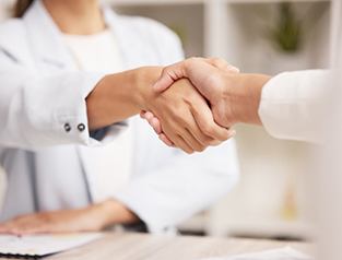 Primer plano de un dentista y un paciente dandose la mano