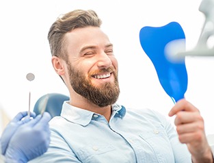 Young man admiring his new dental implants in Greenfield 