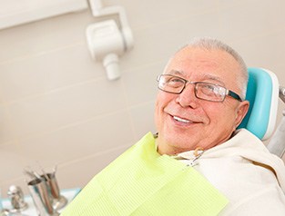 Senior man in dental chair with implant dentures in Greenfield, WI