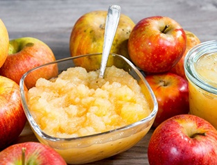 a bowl of applesauce surrounded by apples