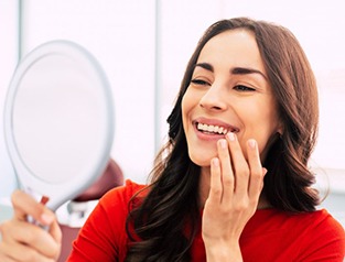 a patient checking her smile with a mirror