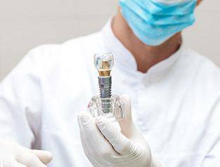 A dentist holding a model of a dental implant