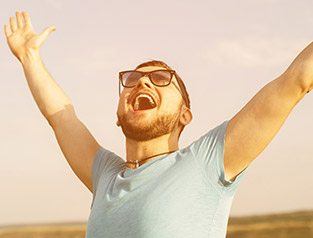 man smiling with arms up in the air