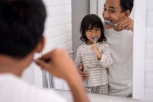 parent brushing their teeth with their child