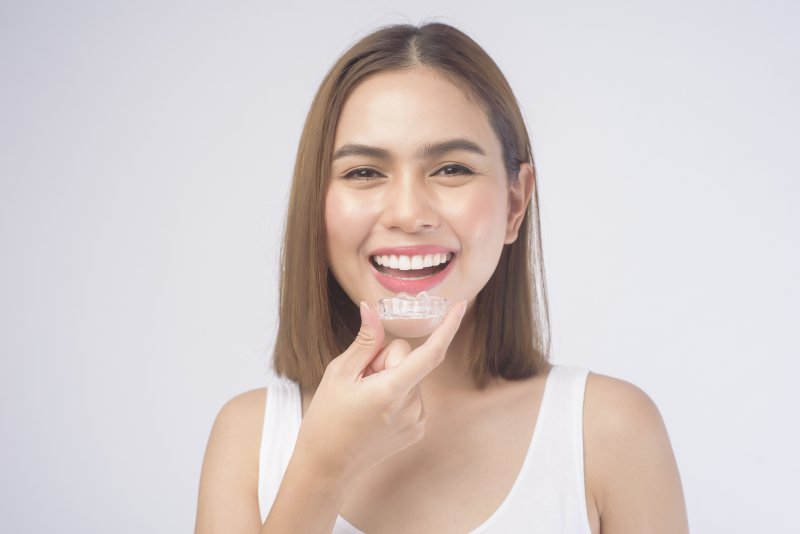 girl smiling and holding Invisalign aligner