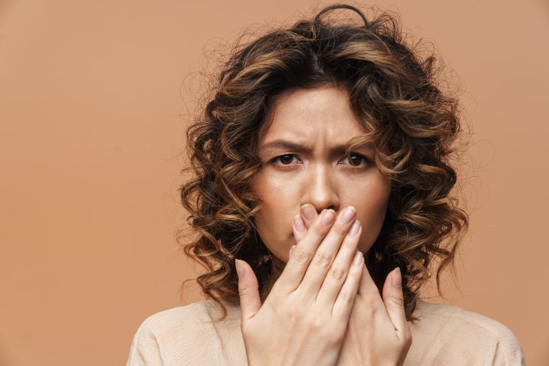 young woman frowning and covering mouth