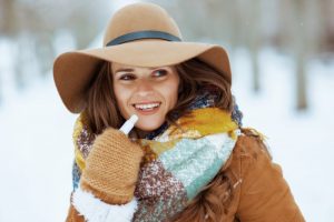 woman applying lip balm in winter outdoors 