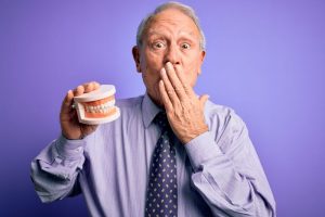 worried man holding dentures