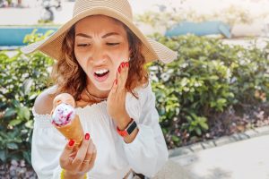 Woman eating ice cream and experiencing tooth sensitivity.