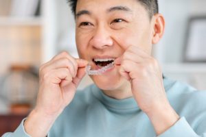 a person putting Invisalign trays in their mouth